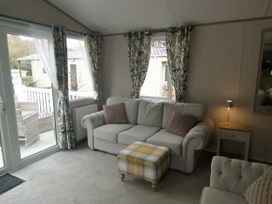 A snug with a sofa and footstool at Aberdunant Hall Holiday Park - Holiday Accommodation 19035, Porthmadog