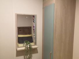 A mirror with a plant and a wardrobe in a bedroom at Aberdunant Hall Holiday Park - Holiday Accommodation 19035, Porthmadog