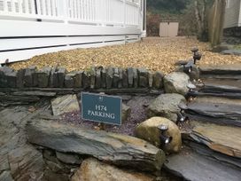 A parking area with a sign and stone steps at Aberdunant Hall Holiday Park - Holiday Accommodation 19035 Porthmadog