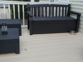 A seating area with a bench, coffee table, and lantern at Brynowen Holiday Park - Holiday Accommodation 19041 Borth Mis Wales