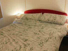 A bed with floral patterned linens and pillows at Brynowen Holiday Park - Holiday Accommodation 19041 Borth Mis Wales