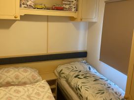 A bedroom with two beds and a shelf of toy cars at Brynowen Holiday Park - Holiday Accommodation 19041 in Borth Mis Wales