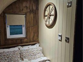 a bedroom with a bed, wooden walls, a window, and a wall decoration at Standen Lodge - Holiday Accommodation 19045, Mablethorpe