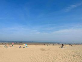 a sandy beach with people sunbathing and colorful umbrellas at Standen Lodge - Holiday Accommodation 19045, Mablethorpe