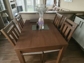 A dining table with chairs and a vase at Whitehouse Leisure Park - Holiday Accommodation 19057, Towyn, Abergele