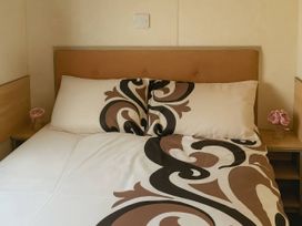 A bed with pillows and a nightstand at Golden Gate Holiday Centre - Holiday Accommodation 19059, Towyn