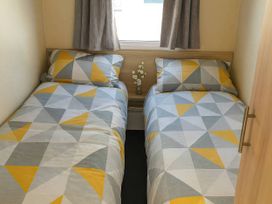 A bedroom with two beds and a small table with flowers at Golden Gate Holiday Centre - Holiday Accommodation 19059 Towyn