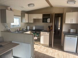 A kitchen with cabinets, sink, stove, microwave, and refrigerator at Southview Holiday Park - Holiday Accommodation 19123 Skegness