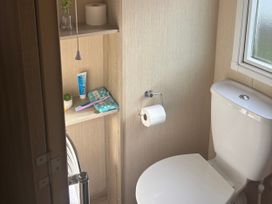 A bathroom with a toilet and shelf containing toiletries at Southview Holiday Park - Holiday Accommodation 19123, Skegness