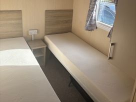 A bedroom with two single beds and a nightstand at Southview Holiday Park - Holiday Accommodation 19123, Skegness