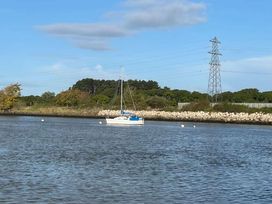 a sailboat on water near a rocky shore with trees and power lines at Rockley Park - Holiday Accommodation 19386, Poole