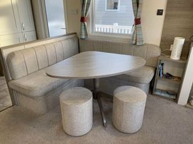 a dining area with a corner bench and round stools at Rockley Park - Holiday Accommodation 19386, Poole