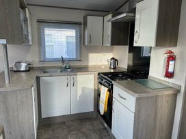 a kitchen with cabinets, a sink, a stove, and a window at Rockley Park - Holiday Accommodation 19386, Poole