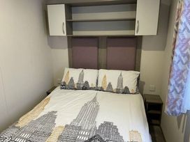 a bedroom with a bed featuring a cityscape design and storage shelves above at Rockley Park - Holiday Accommodation 19386, Poole