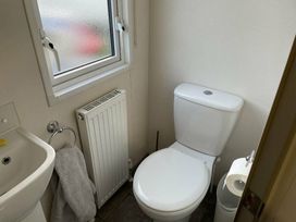 a bathroom featuring a toilet, sink, radiator, and window at Rockley Park - Holiday Accommodation 19386, Poole