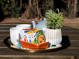 A tray with cups, cookies, a teapot, and a plant in an outdoor dining area at Lido Leisure Park - Holiday Accommodation 19726 Knaresborough