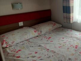 A bedroom with a bed and floral sheets at Hunters Quay Holiday Village in Dunoon