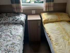 A bedroom with two beds and a bedside table at Hunters Quay Holiday Village in Dunoon