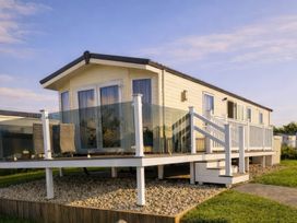 A holiday home with deck and glass railing at Primrose Valley Holiday Park - Holiday Accommodation 20012, Filey