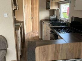 a kitchen with wooden cabinets and a gas stove at Golden Sands Park - Holiday Accommodation 20105 in Ingoldmells, Skegness