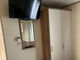 a television mounted on a wall with a cabinet and a mirror at Golden Sands Park - Holiday Accommodation 20105 in Ingoldmells, Skegness