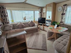 a living room with a sofa, a TV, a dining table, and windows at Golden Sands Park - Holiday Accommodation 20105 in Ingoldmells, Skegness