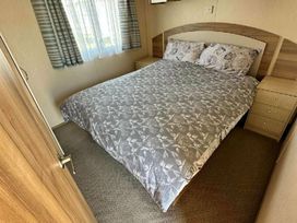 a bedroom with a bed covered in a patterned duvet and bedside tables at Golden Sands Park - Holiday Accommodation 20105 in Ingoldmells, Skegness