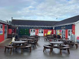 an outdoor area with wooden picnic tables and a game zone at Golden Sands Park - Holiday Accommodation 20105 in Ingoldmells, Skegness
