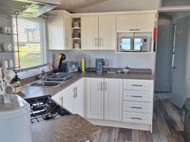 A kitchen with appliances and cabinets at Liskey Hill Caravan Park - Holiday Accommodation 20197, Perranporth