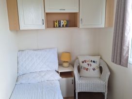 A bedroom with a bed and a chair at Liskey Hill Caravan Park - Holiday Accommodation 20197, Perranporth