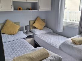 A bedroom with two single beds and a small table at Liskey Hill Caravan Park - Holiday Accommodation 20197, Perranporth