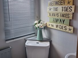 A bathroom with a toilet and a vase of flowers at Liskey Hill Caravan Park - Holiday Accommodation 20197, Perranporth