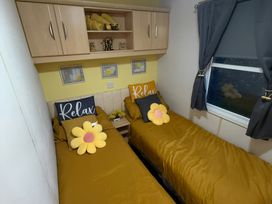 A bedroom with two beds and a shelf at Red Lion Holiday Park - Holiday Accommodation 20228, Arbroath