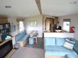 a living room and dining area with seating and kitchenette at Perran Sands - Holiday Accommodation 20230 in Perranporth