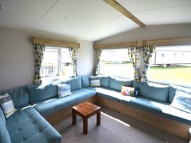 a living room with a sectional sofa and a wooden coffee table at Perran Sands - Holiday Accommodation 20230, Perranporth