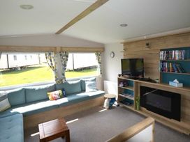 a living room with a blue sofa, television, and fireplace at Perran Sands - Holiday Accommodation 20230, Perranporth