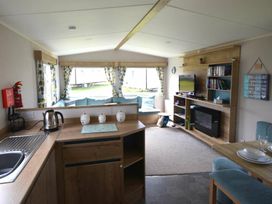 a living room with a kitchenette and seating area at Perran Sands - Holiday Accommodation 20230, Perranporth