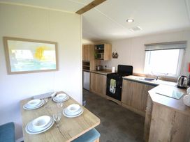 a kitchen area with a dining table set for four at Perran Sands - Holiday Accommodation 20230 Perranporth