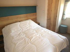 a bedroom with a double bed and wooden headboard at Perran Sands - Holiday Accommodation 20230, Perranporth