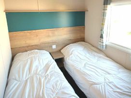 a bedroom with two single beds and a wooden headboard at Perran Sands - Holiday Accommodation 20230 in Perranporth