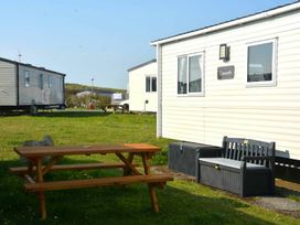a picnic table and bench outside a mobile home at Perran Sands - Holiday Accommodation 20230 in Perranporth