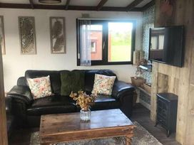 a living room with a black sofa, wooden coffee table, and window at Hafan y Mor Haven - Holiday Accommodation 20258, Pwllheli