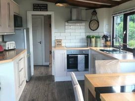 a kitchen with cabinets, a stove, and a dining table at Hafan y Mor Haven - Holiday Accommodation 20258 Pwllheli