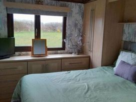 a bedroom with a bed, a window, and a dresser at Hafan y Mor Haven - Holiday Accommodation 20258 in Pwllheli