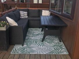 a seating area with a black sectional sofa and a table on a patterned rug at Hafan y Mor Haven - Holiday Accommodation 20258 in Pwllheli