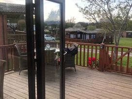 a deck with chairs and a table overlooking a grassy area at Hafan y Mor Haven - Holiday Accommodation 20258 in Pwllheli