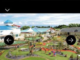 a landscape with miniature golf courses, people playing, and buildings in the background at Hafan y Mor Haven - Holiday Accommodation 20258 in Pwllheli