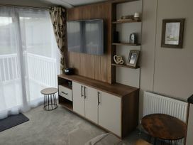 A living room with a television and storage cabinet at Lakeland Leisure Park - Holiday Accommodation 20349 Grange-Over-Sands