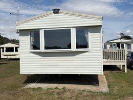 A caravan with a decking area at Skipsea Sands Holiday Park - Holiday Accommodation 20390 Driffield