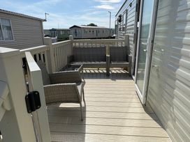A patio with chairs and access door at Skipsea Sands Holiday Park - Holiday Accommodation 20390 Driffield